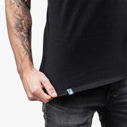 Mann trägt CORESPUN Merino Tank Top Herren 150 g/m², betont durch sichtbares Tattoo auf dem Arm, ideal für Outdoor-Aktivitäten, kombiniert Merinowolle mit synthetischer Robustheit.