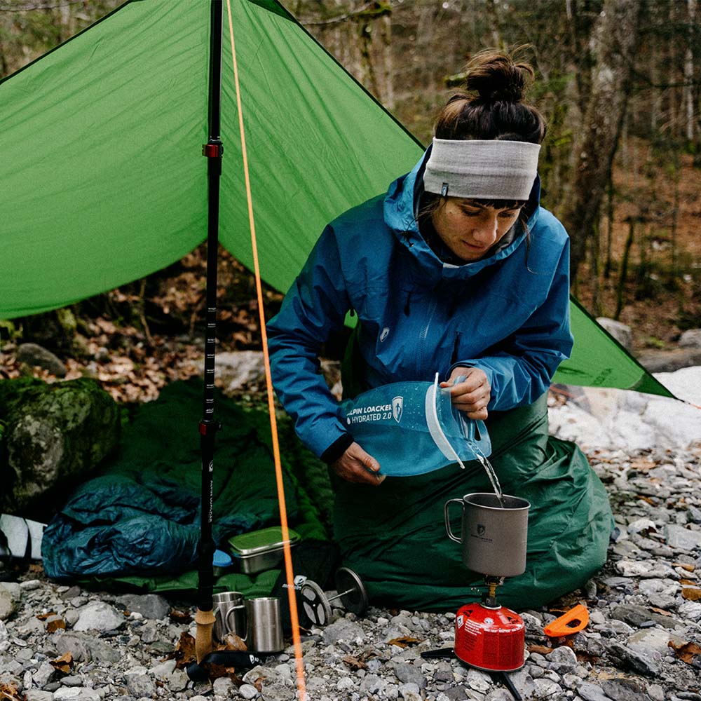 Frau in Zelt gießt Wasser in Trinkblase für Sommer + Winter, ideal für Outdoor-Sport, ultraleicht, robust, einfache Handhabung.