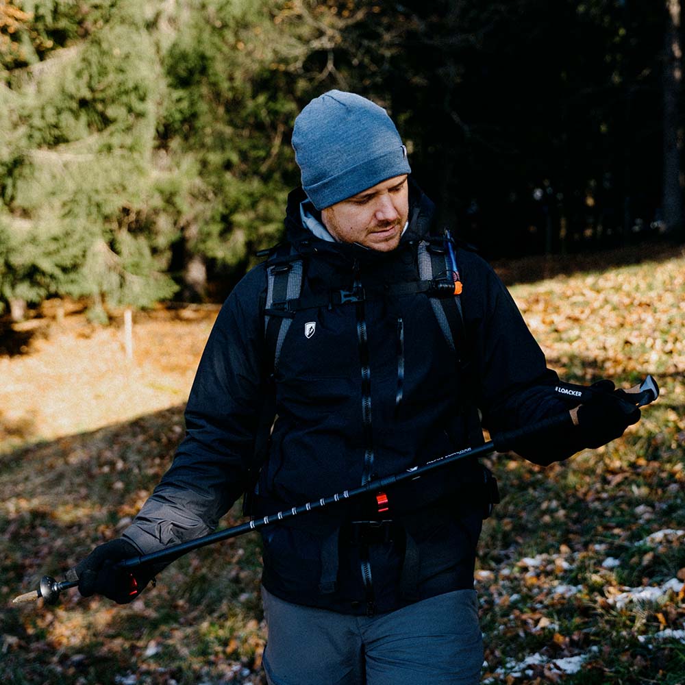 Mann mit Teleskop Wanderstöcken aus Aluminium von Alpin Loacker, geeignet für Outdoor-Abenteuer wie Wandern und Trekking, in natürlicher Umgebung.