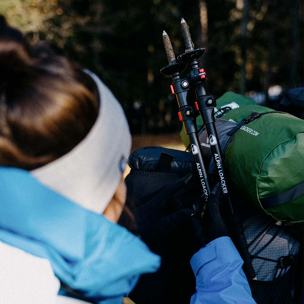 Frau mit Rucksack und Teleskop Wanderstöcken aus Aluminium von Alpin Loacker, ideal für Outdoor-Abenteuer wie Wandern und Trekking.